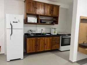 a kitchen with a white refrigerator and wooden cabinets at Apto de ferias em Bertioga Maitinga in Bertioga