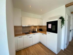 eine Küche mit weißen Schränken und einem schwarzen Gerät in der Unterkunft Apartment in Saalfelden near Ski Slopes in Saalfelden am Steinernen Meer