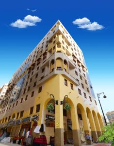 um edifício amarelo alto com um céu azul ao fundo em Al Mukhtara Golden em Medina