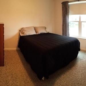 a bedroom with a black bed with a window at The Lodge at Lyman's in Houghton Lake +6 photos