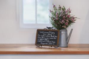 una señal sentada en un mostrador con un jarrón de flores en Cottage on Lamington, en Canungra