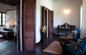 a room with a door and a living room with a table at Satri House Hotel in Luang Prabang