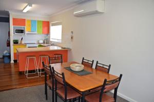 a kitchen and dining room with a wooden table and chairs at Mariner 16 Flat 2 - Bring your own linen. in South West Rocks