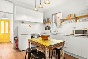 a kitchen with white cabinets and a wooden table at 'Enmore Lane' A Central Eclectic Artist Escape in Sydney