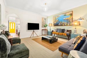 a living room with couches and a flat screen tv at 'Enmore Lane' A Central Eclectic Artist Escape in Sydney