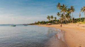 una spiaggia con palme e una barca in acqua di Lam Ha Resort a Phu Quoc