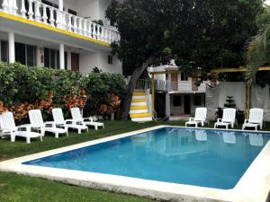 a swimming pool in the yard of a house with white chairs at Hotel Los Angeles in Tequesquitengo