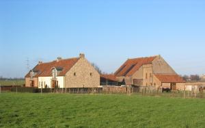un grupo de edificios en un campo junto a un campo en Vakantiewoning Venderhof, en Maaseik