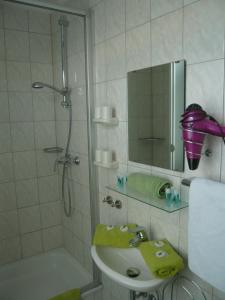 a bathroom with a sink and a shower with a mirror at Pension Louisa in Dagebüll