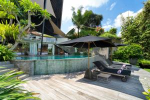 a patio with an umbrella and a bench next to a pool at Villa Toraja A Hidden Luxury Retreat in the canggu in Canggu