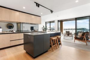Wynyard Quarter Apartments by Urban Rest في أوكلاند: مطبخ مع جزيرة كبيرة في غرفة بها نوافذ