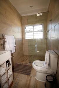 uma casa de banho com um WC e um chuveiro com uma janela em Westward HO Apartment 13 em Cidade do Cabo