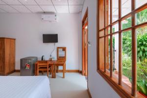 Un dormitorio con una cama y un escritorio y una ventana. en Resort Hien Minh Bungalow, en Phu Quoc