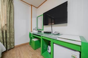 a room with a green desk with a flat screen tv at Happy Hotel in Jeju