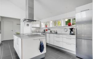 a kitchen with white cabinets and a stainless steel refrigerator at Holiday Home Stege 35 in Pollerup Kullegård