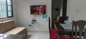 a living room with a table and a television on the wall at Sua casa longe de casa in Mongaguá