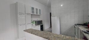 a kitchen with white appliances and a counter top at Sua casa longe de casa in Mongaguá +7 photos