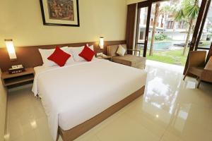 a bedroom with a large white bed with red pillows at Grand La Walon Hotel in Legian