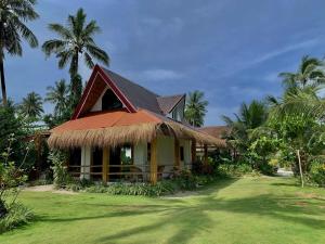 a house with a thatched roof and a yard at Helmina's Villas in General Luna