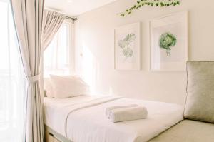 a bedroom with a bed with white sheets and a window at Simple and Cozy Living Studio Room at Poris 88 Apartment By Travelio in Tangerang +15 photos