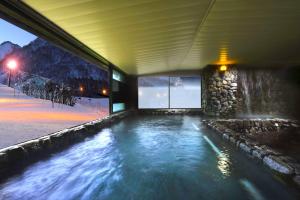 a swimming pool in a house in the snow at Hotel Green Plaza Hakuba in Otari