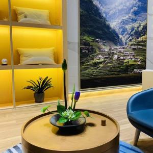 Atour Hotel Suzhou Jinji Lake Expo Center في سوتشو: غرفة معيشة مع طاولة وجدار اصفر