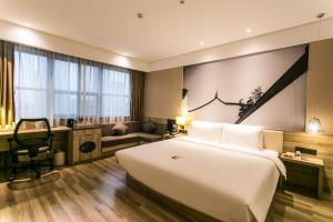 Atour Hotel Suzhou Jinji Lake Expo Center في سوتشو: غرفة فندقية بها سرير كبير ومكتب