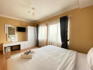 a bedroom with a white bed with a towel on it at Cozy Furnished 3BR at Grand Setiabudi Apartment By Travelio in Bandung +36 photos