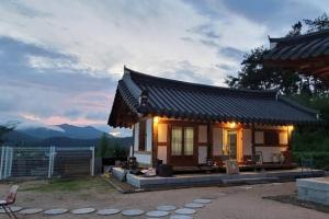 a small house with a roof with mountains in the background at Lee Cho Hanok in Gyeongju