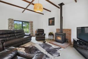 a living room with a leather couch and a fireplace at Clarendon Estate - Masterton Holiday Home in Masterton