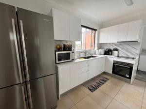 a kitchen with white cabinets and a stainless steel refrigerator at Alison's central apartment in Cabramatta