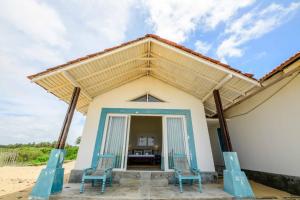 a house on the beach with two chairs and a table at Bedrock Beach Villas in Kalpitiya