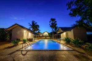 a swimming pool in front of a house at night at Bedrock Beach Villas in Kalpitiya