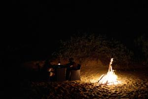 a group of people sitting at a table next to a fire at Bedrock Beach Villas in Kalpitiya