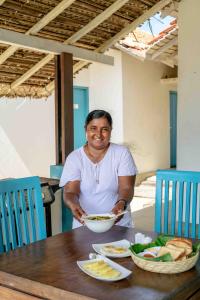 a woman standing at a table with a bowl of food at Bedrock Beach Villas in Kalpitiya