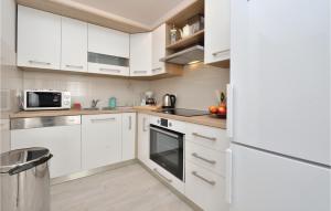 Biała kuchnia z białymi szafkami i urządzeniami w obiekcie Apartment Vrsi-Mulo 11 w mieście Kod Mula