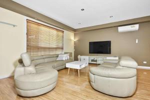 Una sala de estar con un sofá y dos sillas y un televisor. en Your Home Retreat in Maribyrnong, en Melbourne