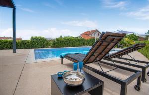 una sedia e un tavolo accanto alla piscina di Beach Front Home In Tribunj a Tribunj (Trebocconi)