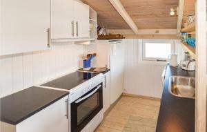 ヒアツハルスにあるHoliday Home Klitrenden Hirtshals Viのキッチン(白いキャビネット、黒いカウンタートップ付) +6枚の写真