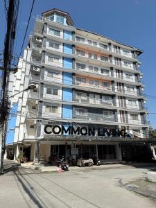un gran edificio de apartamentos con un cartel en Common Living, en Chiang Mai