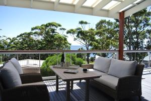 a patio with a table and chairs on a deck at Oceandeck House in Ulladulla