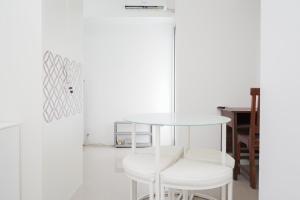 a white table and two white stools in a room at New and Simply Studio at Urbantown Serpong Apartment By Travelio in Tangerang