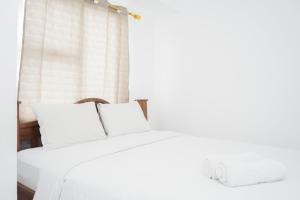 a white bed with white pillows and a window at New and Simply Studio at Urbantown Serpong Apartment By Travelio in Tangerang +8 photos