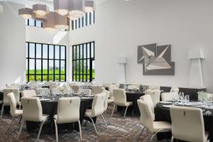 a dining room with tables and chairs and windows at Hilton Garden Inn Orlando I-4 Millenia Blvd Mall in Orlando