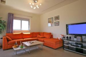 ラクハニアにあるOuranos Villaのリビングルーム(オレンジ色のソファ、薄型テレビ付)