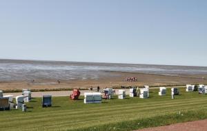 a group of chairs sitting on the grass near the beach at Friedrichskoog-Deichblick 4 in Friedrichskoog