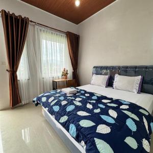 ein Schlafzimmer mit einem Bett mit einer blau-weißen Bettdecke in der Unterkunft Sapo Rumbia Homestay in Berastagi