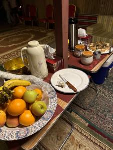 a table with plates of fruit on top of it at Golden dune Bedouin camp in Al Wāşil