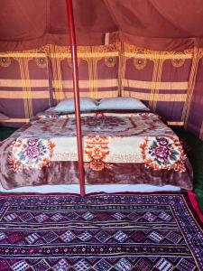 a bed in a tent in a room at Golden dune Bedouin camp in Al Wāşil