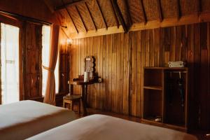 a bedroom with wooden walls and a bed and a window at The Tamban Jukung in Nusa Penida